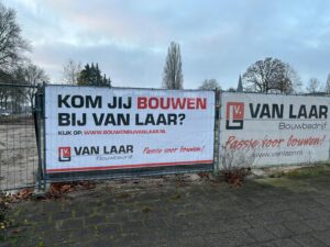 Bouwdoek van Bouwbedrijf Van Laar met de oproep ‘Kom jij bouwen bij Van Laar?’ op een bouwplaats in de regio.