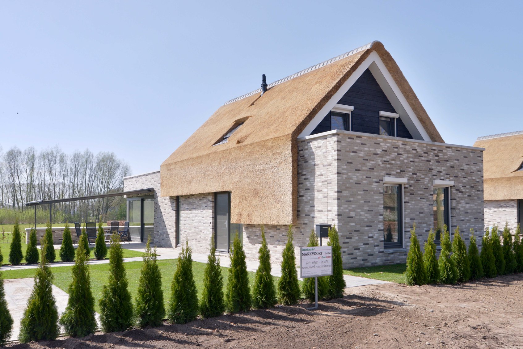 Karakteristieke woning met rieten kap en moderne architectuur.