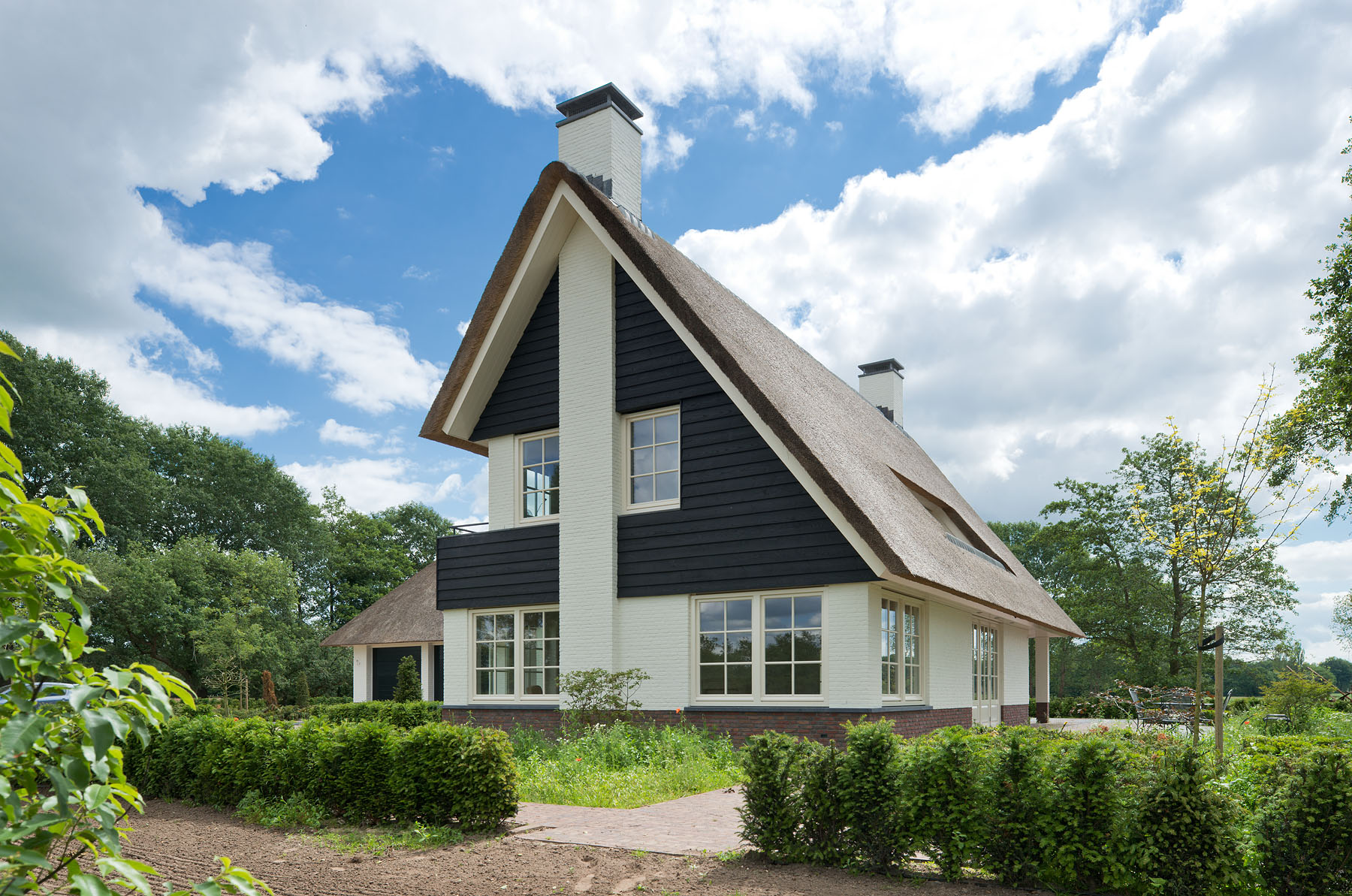 Landelijke woning met rieten dak en natuurlijke uitstraling.